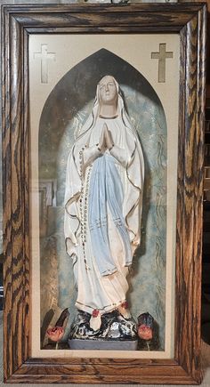 a statue of the virgin mary in a wooden frame