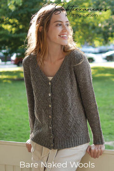 a woman wearing a brown cardigan standing next to a fence