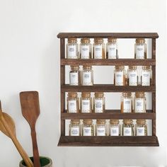 a wooden shelf filled with jars and spoons next to a wall mounted spice rack