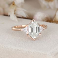 an engagement ring with three diamonds on it and a white flower in the back ground