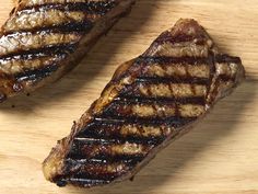 two pieces of steak sitting on top of a wooden cutting board next to each other