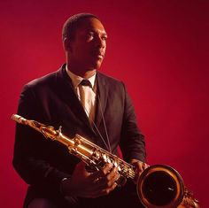 a man in a suit and tie holding a saxophone