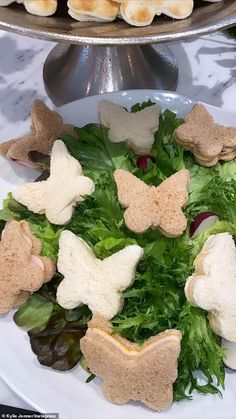 a white plate topped with lots of lettuce and butterfly shaped food pieces on top of it