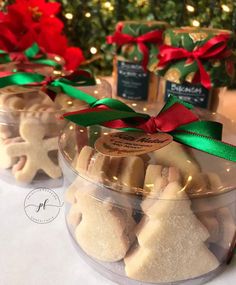 three plastic containers filled with christmas cookies on top of a table next to a green and red ribbon