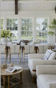 a living room filled with furniture and windows next to a wooden table in front of a white couch