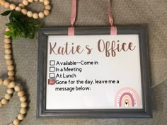 a sign that says kate's office hangs on the wall next to a bead necklace