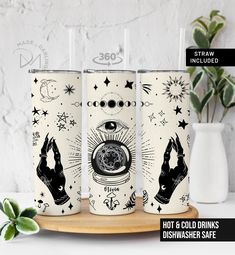 three tumbles with different designs on them sitting on a table next to a potted plant