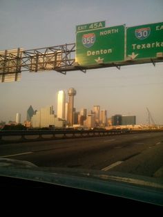 an interstate exit sign with the city skyline in the background