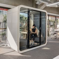 a woman sitting on a chair in a room with glass walls