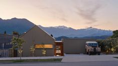 a truck is parked in front of a house with mountains in the background at dusk