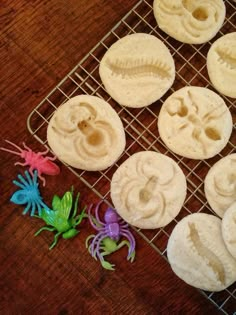 some cookies are sitting on a cooling rack with fake bugs and spider toys next to them