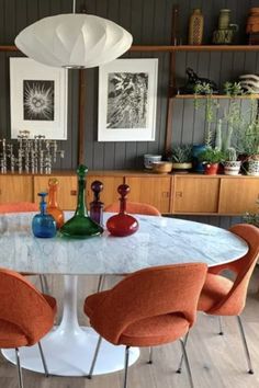 a dining room table with orange chairs around it