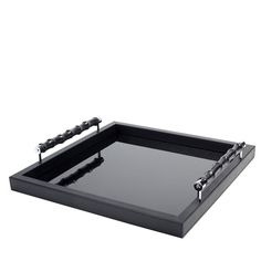 a black tray with metal handles and chains on the bottom, sitting on a white surface