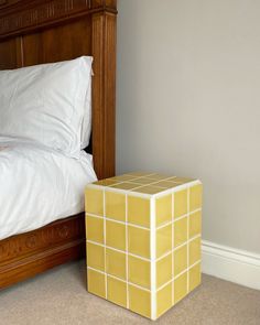 a small yellow cube sitting on the floor next to a bed