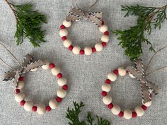 three christmas wreaths made out of beads and pine needles on a gray cloth background