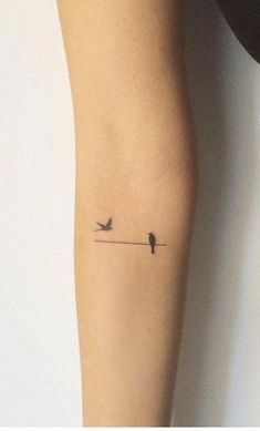 a small bird on a wire tattoo on the leg, with two birds sitting on it