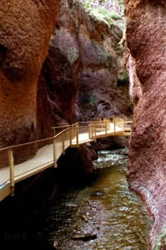 a wooden bridge over a small stream in a canyon