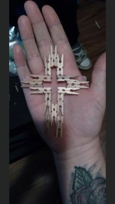 a person's hand holding a small cross made out of wooden sticks and nails