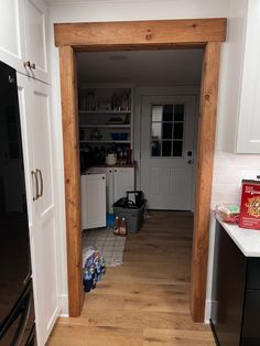 an open door leading to a kitchen with white cabinets and black appliances in the background