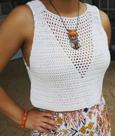 a woman standing with her hands on her hips wearing a white top and colorful shorts