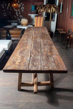 an old wooden table is in the middle of a room with chairs and couches