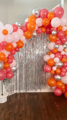 an arch made out of balloons and streamers on a wooden floor in front of a mirror