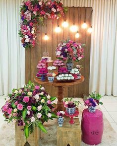 a table topped with cakes and cupcakes on top of wooden boxes next to flowers