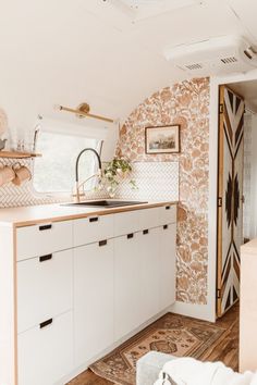 a kitchen with white cabinets and patterned wallpaper on the walls, along with a sink