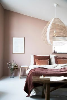 a bedroom with a bed, table and hanging lamp in the corner next to it