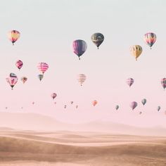 many hot air balloons are flying in the sky over sand dunes and desert terrains