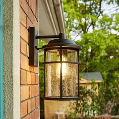 an outdoor light hanging from the side of a building next to a table and chairs