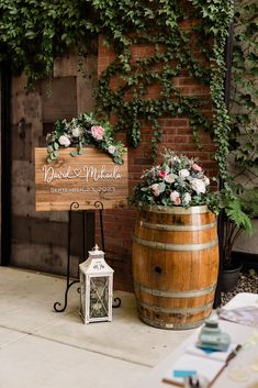 a wooden sign sitting next to a barrel filled with flowers