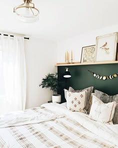 a bed with pillows and blankets in a bedroom next to a window filled with curtains