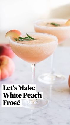 two glasses filled with drinks sitting on top of a marble table next to peaches