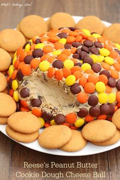 a cake covered in candy and cookies on top of a white plate with a wooden table