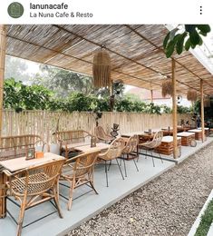 an outdoor dining area with wooden tables and wicker chairs, surrounded by greenery