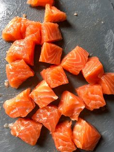 raw salmon on a cutting board ready to be cut into bite sized pieces and put in the oven