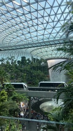 the inside of a building with many people walking around and looking at some water features