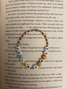 an open book with a colorful beaded bracelet on it's cover and the words love spelled in small letters