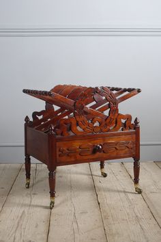 an antique wooden box with wheels and carvings on the top is sitting on a wood floor