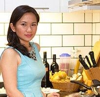 a woman standing in front of a counter filled with food and wine bottles on it