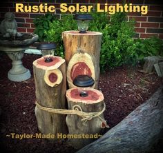 some logs are stacked up in the yard and have lights on top of them for solar lighting