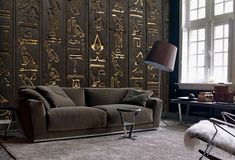 a living room filled with furniture next to a wall covered in gold egyptian stencils