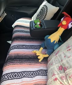 stuffed animals are sitting on the back seat of a car, next to pillows and blankets