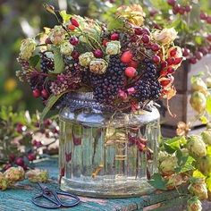 a vase filled with lots of flowers sitting on top of a table next to scissors