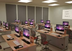 there are many computers on the desks in this class room, all with their screens turned on