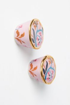 two pink and gold ear plugs with floral designs on the top one has a golden rim