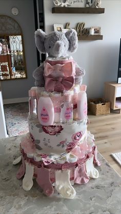 a multi layer baby shower cake with teddy bear on top and pink diapers around the edges