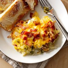 a white plate topped with an omelet next to a slice of bread on top of a wooden table