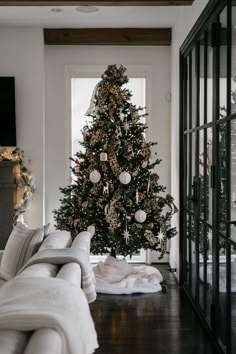 a living room with a christmas tree in the corner and white couches on the floor